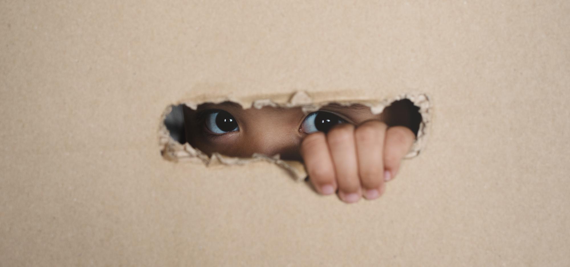 Young girl peeping through cardboard