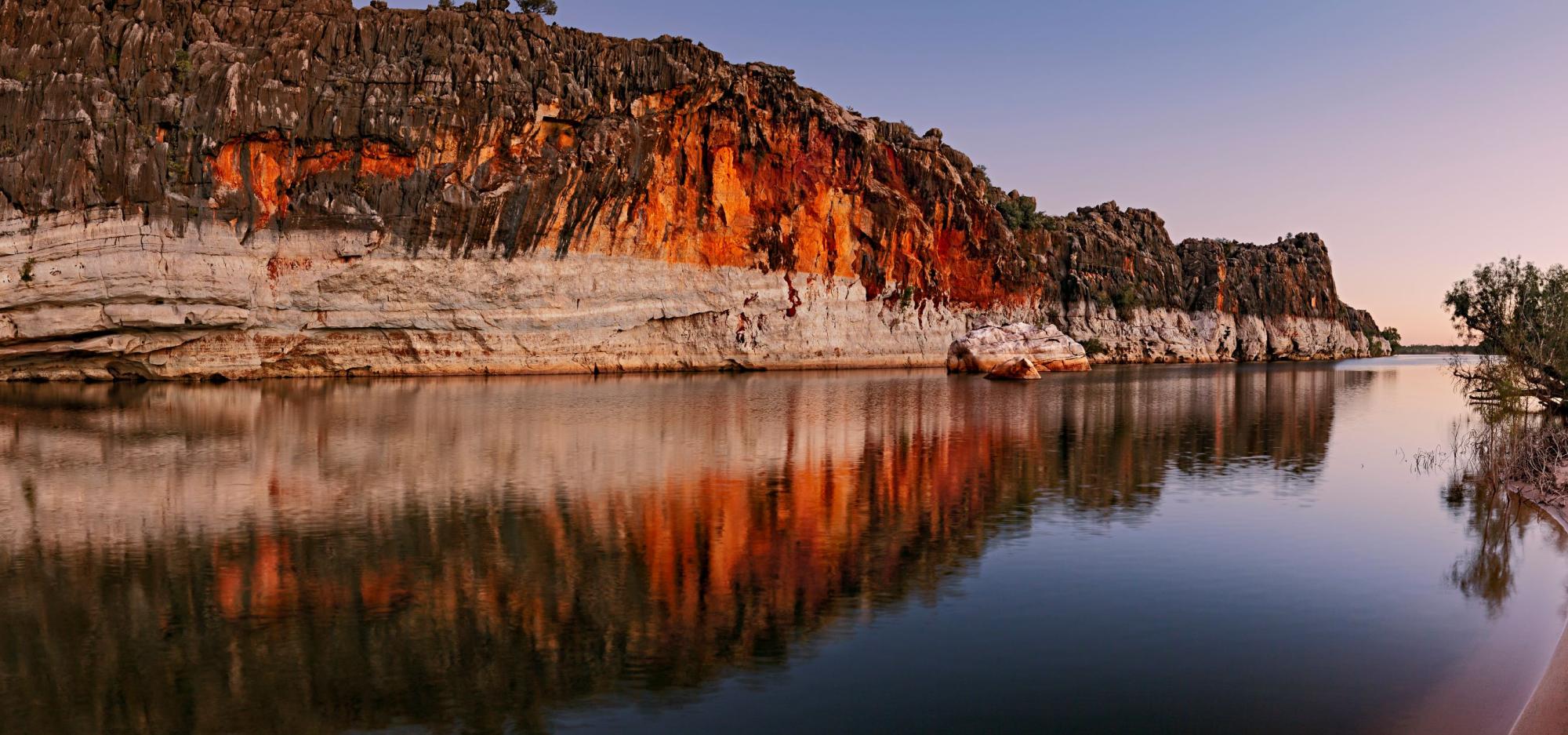 Danggu Geikie Gorge Twilight, a cliff face going into the river at sunset, with reflections on the water