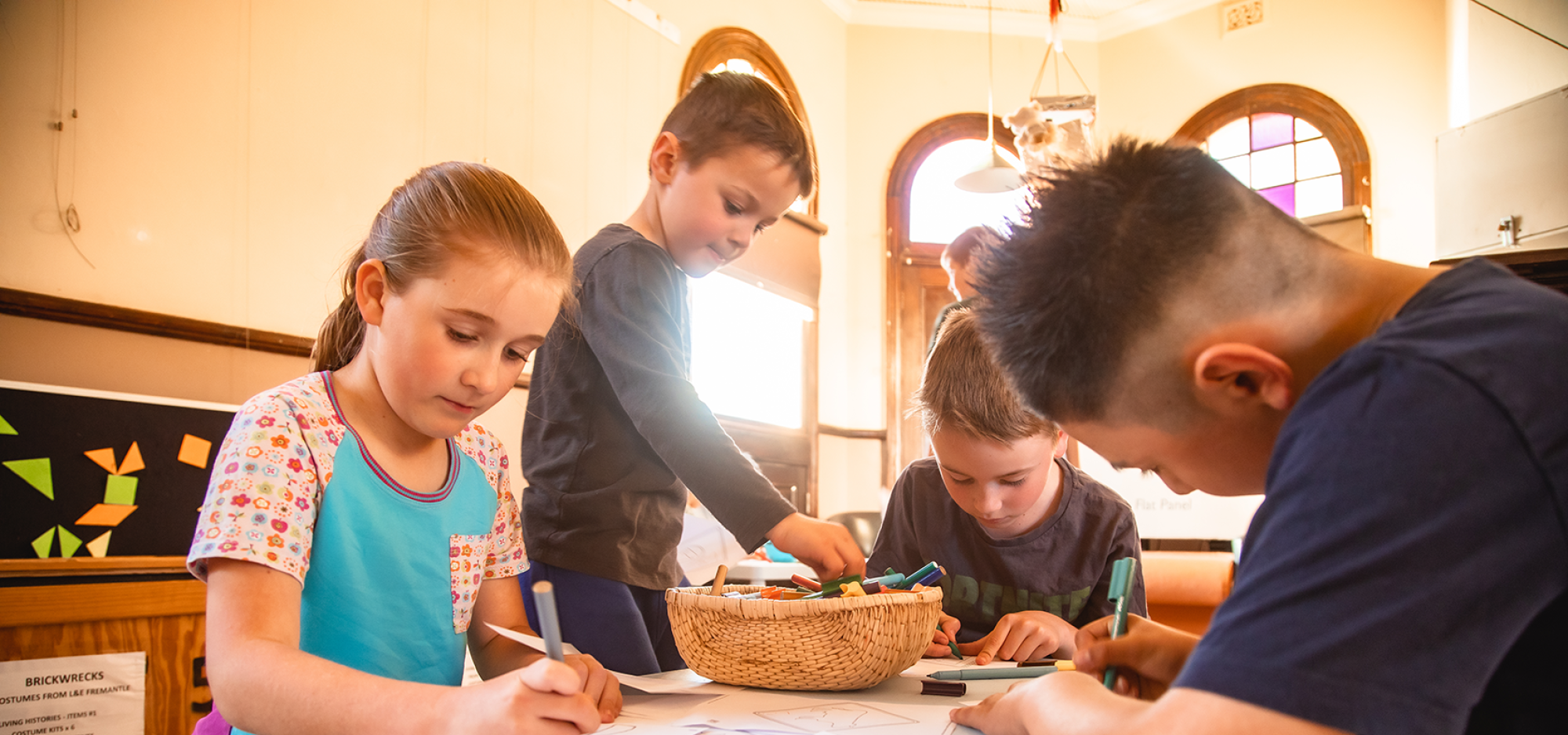 4 children colouring in at a table