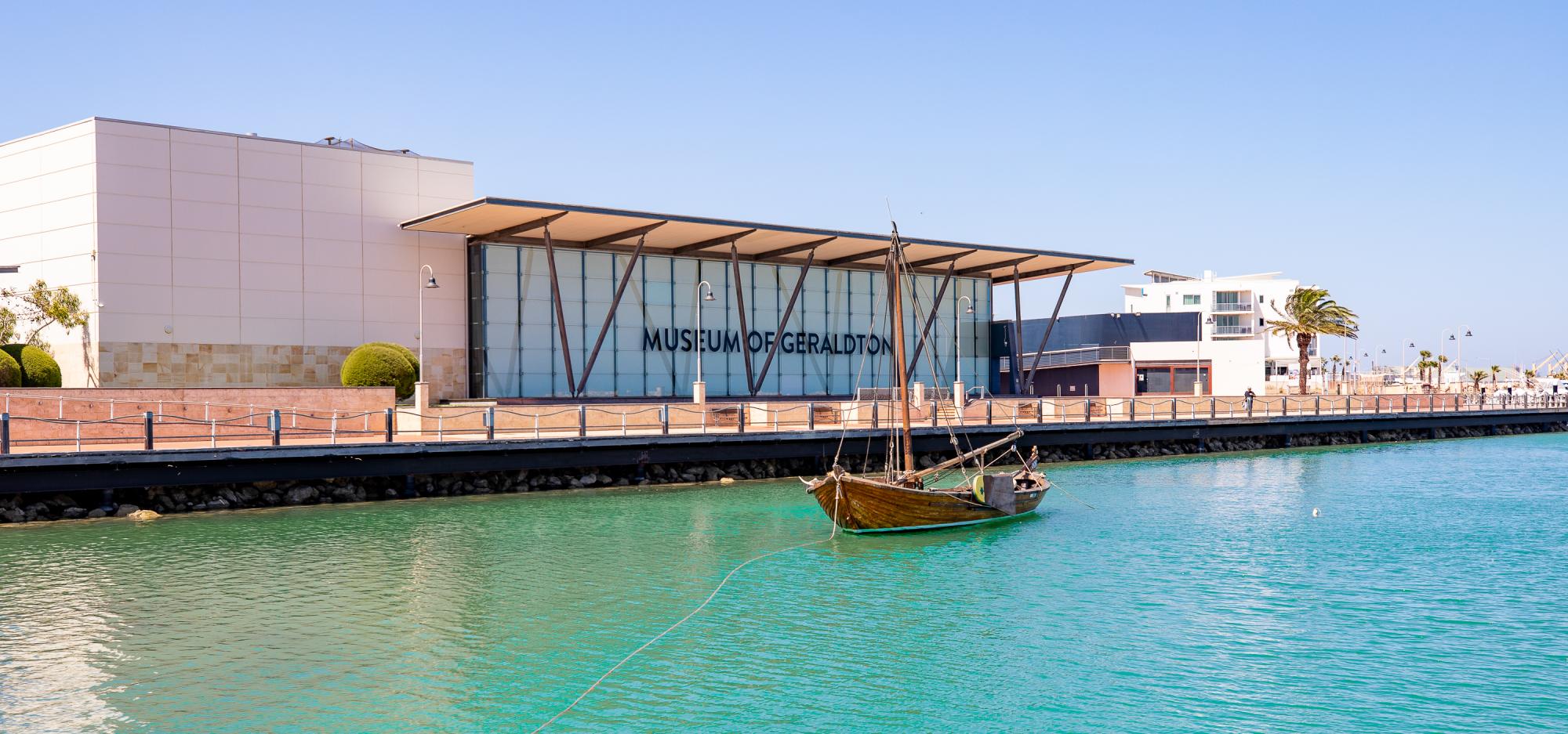 A museum located on a harbour with a boat anchored at the front