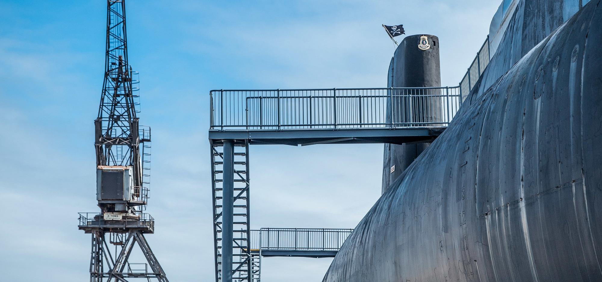 An exterior view of the submarine HMAS Ovens and surrounding slipway beneath a blue sky