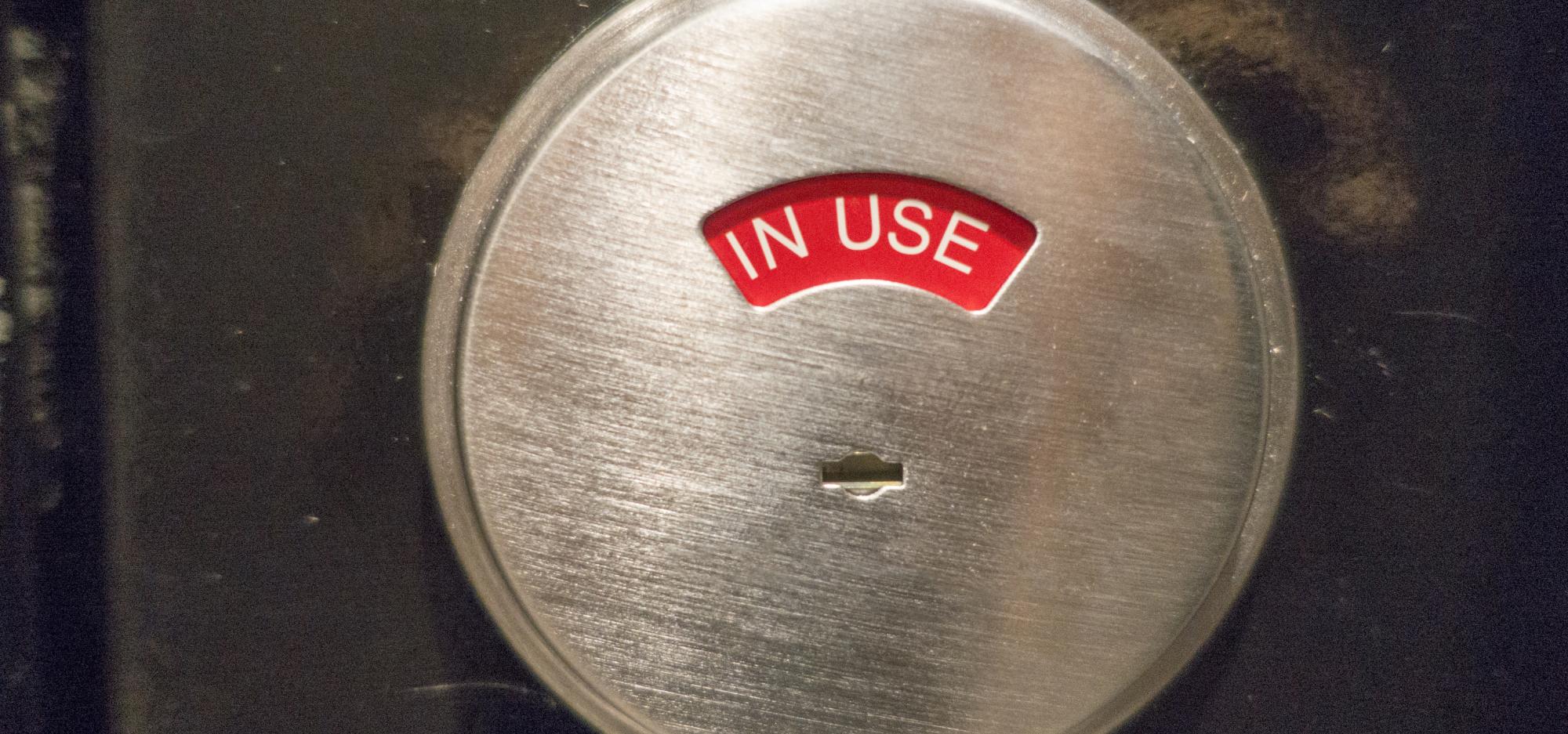 A silver toilet door lock turned to red reading 'occupied'