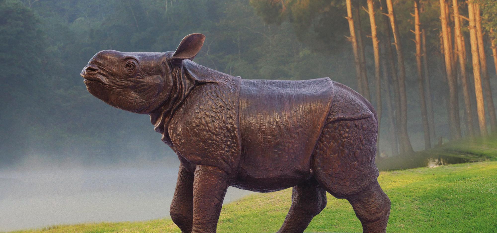 Wild Baby Javan Rhino statue set near a lake on green grass