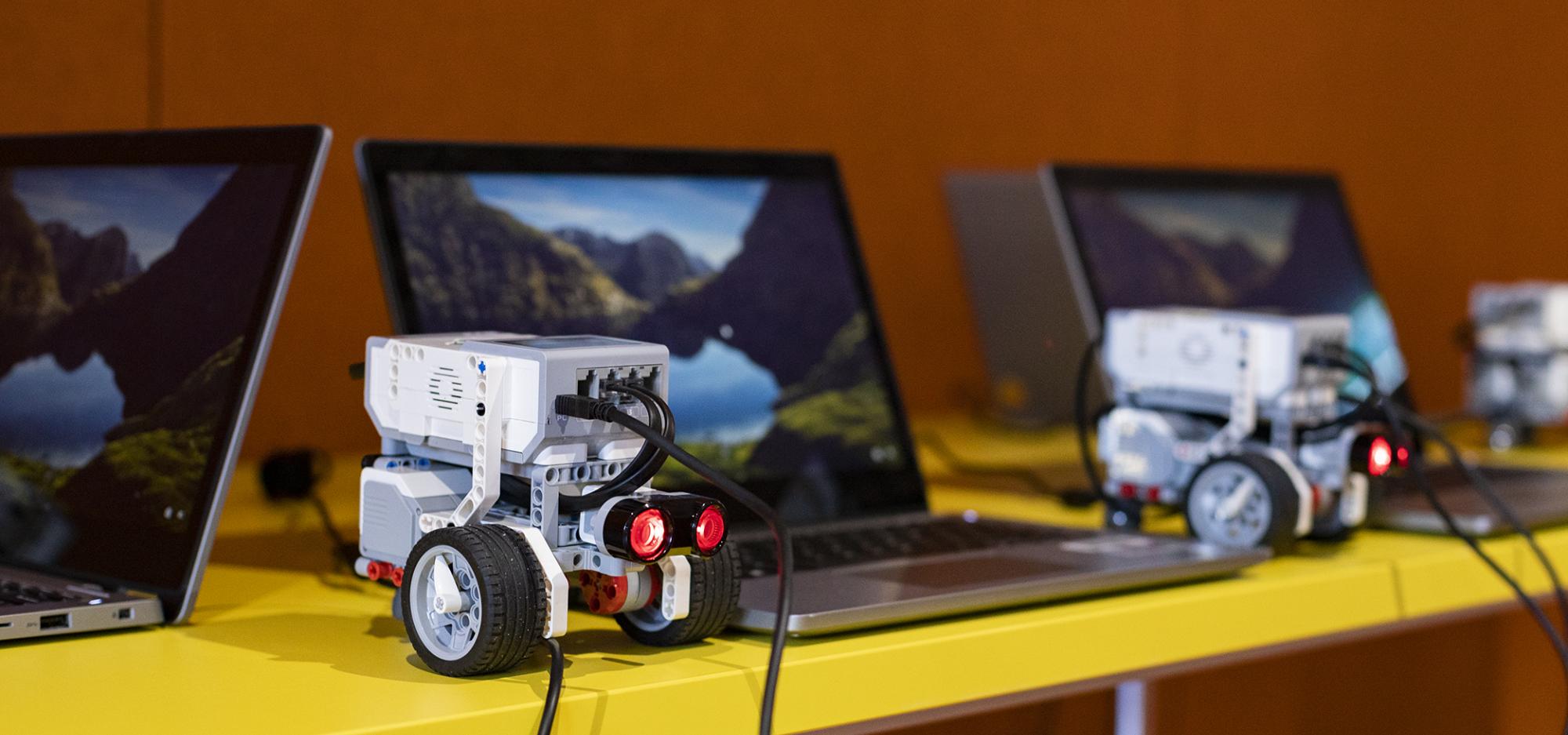 Technology linked to a laptop sits on a yellow desk