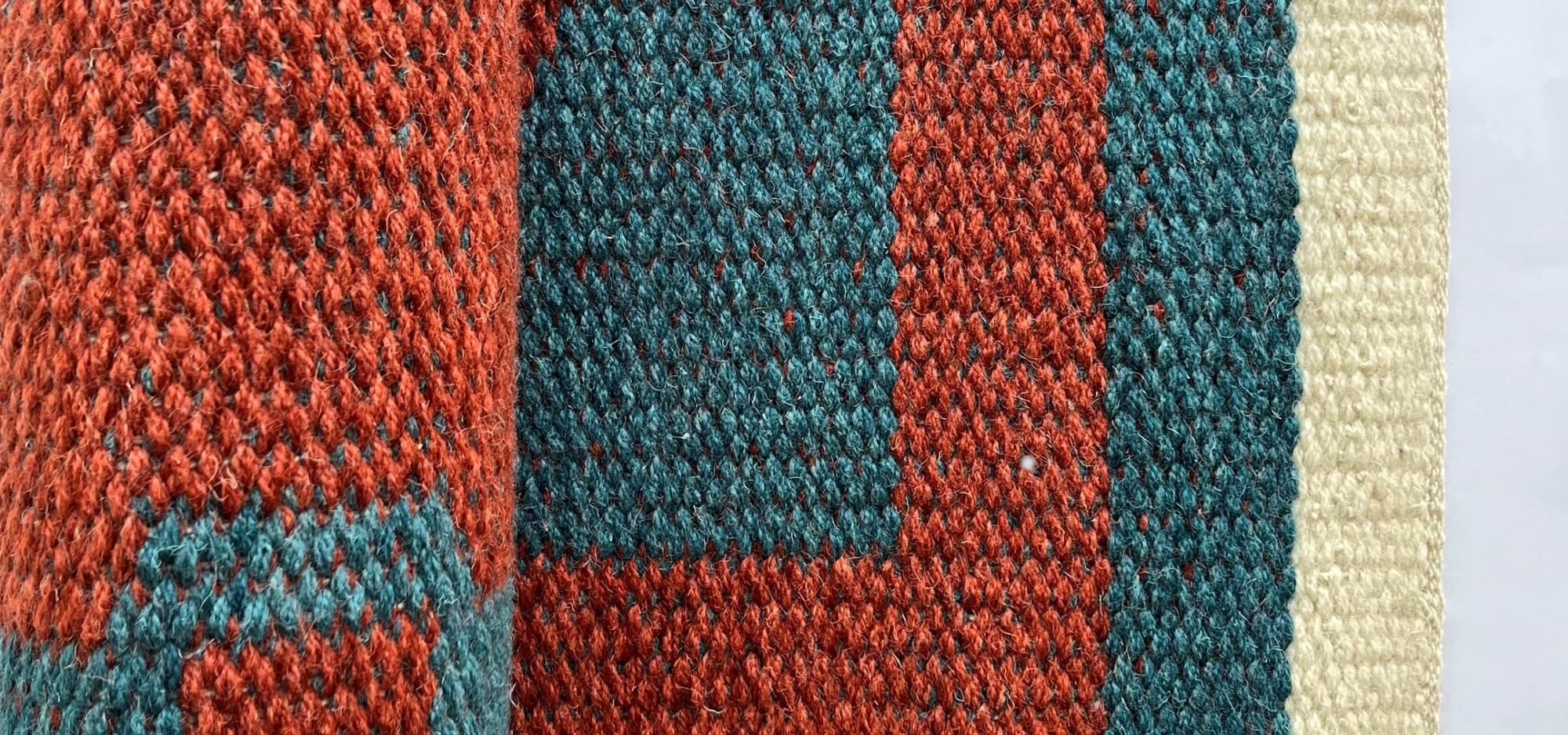 a close up of red and blue colour yarn weaved into a pattern