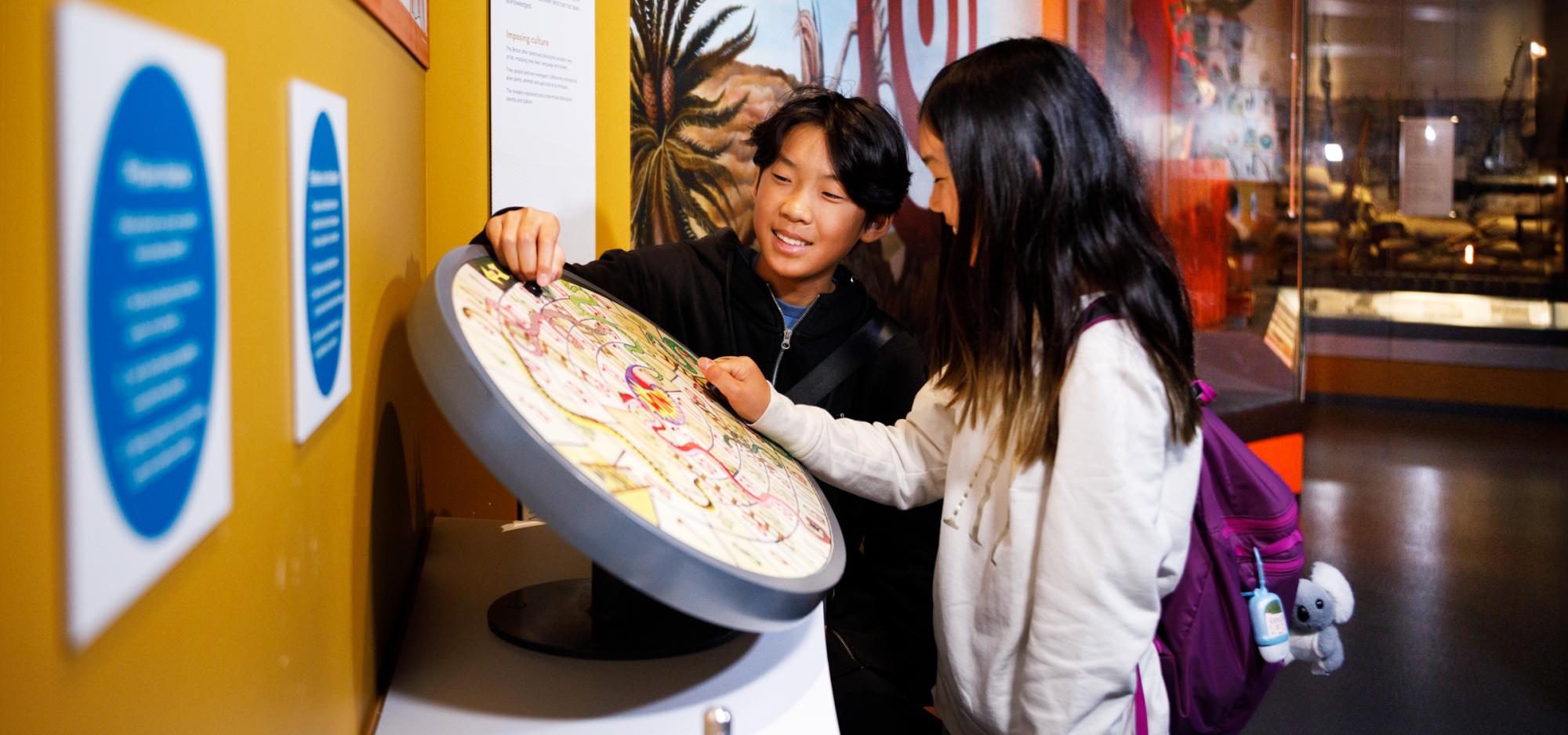 Two children interacting with a round interactive display at a museum.