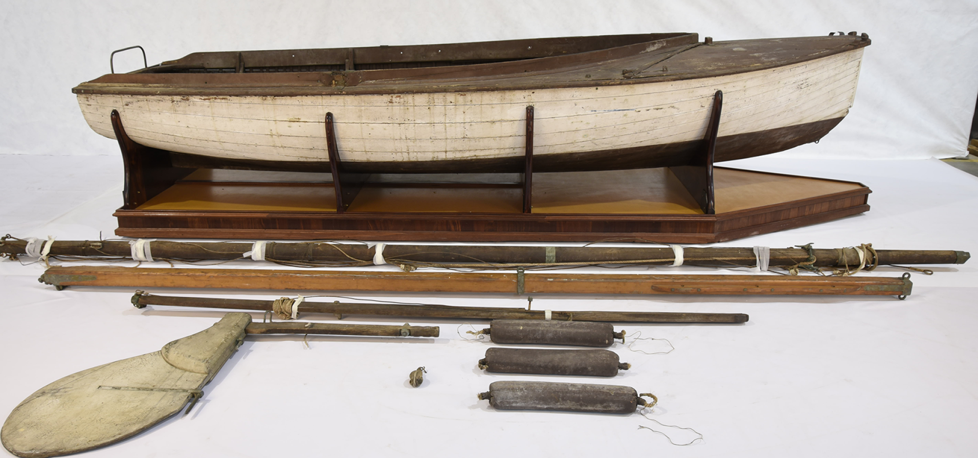 The open built Endeavour is a snub-nosed, carvel planked 14-foot wooden dinghy. It can be rigged as a sloop or a gaff, and has a centreboard, foredeck, and side decks. The hull to the waterline is painted white, while the deck, side benches and underside of the hull are painted brown. The original sail insignia shows the letter “E” inside a red and white diamond.