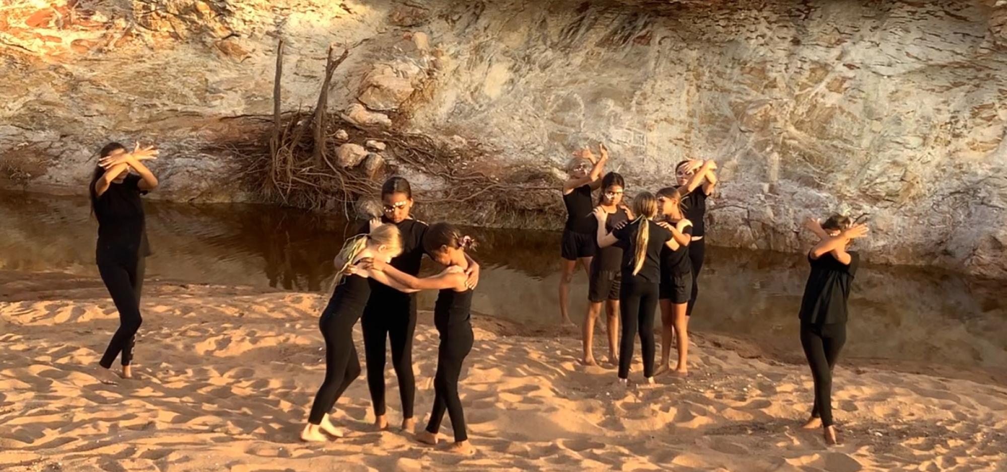 a group of young people stand in poses on the sand