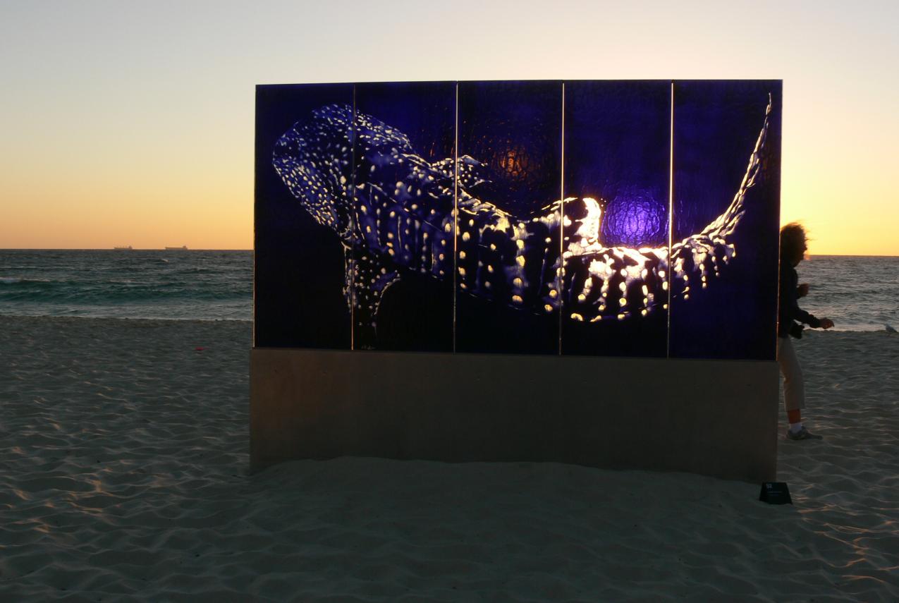 A glass sculpture on display at a beach at sunset