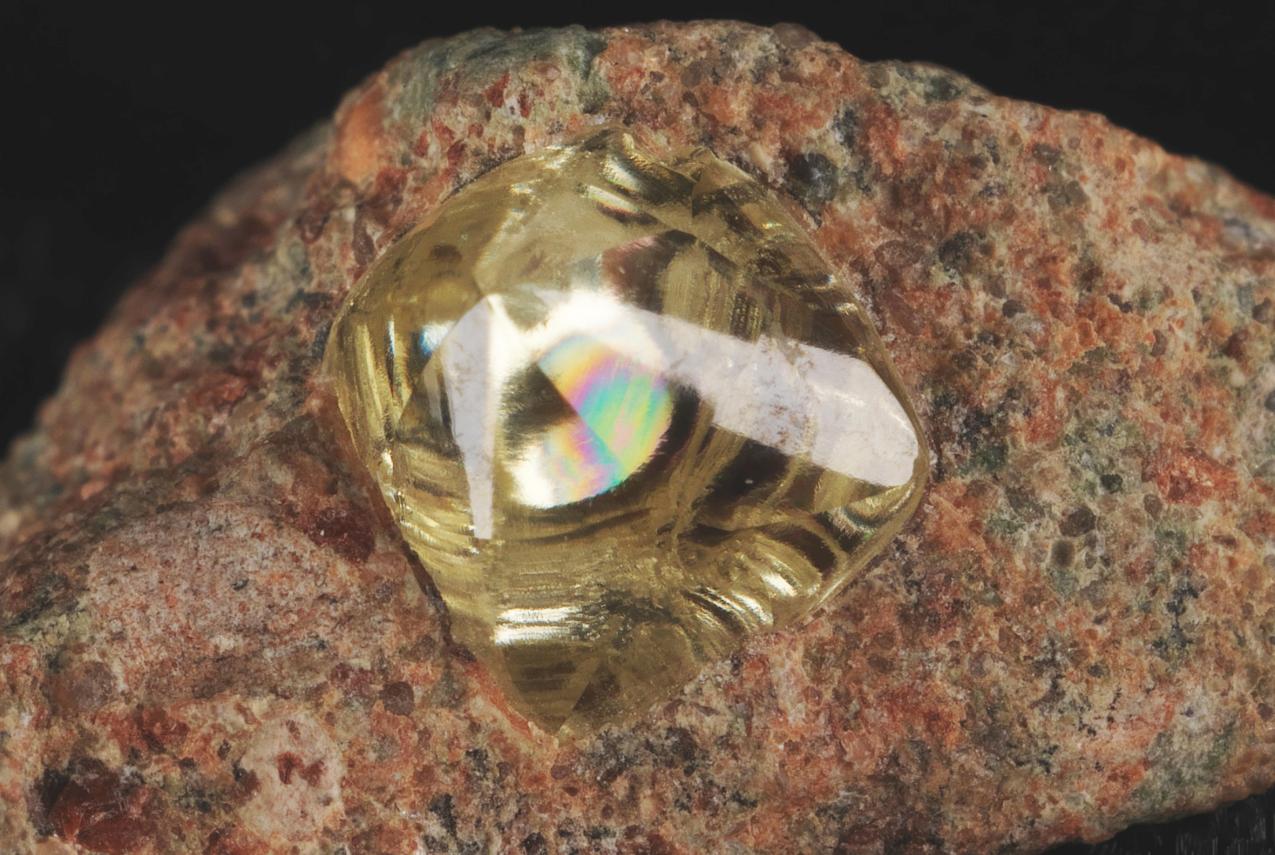 A yellow diamond trapped within a red and brown speckled rock
