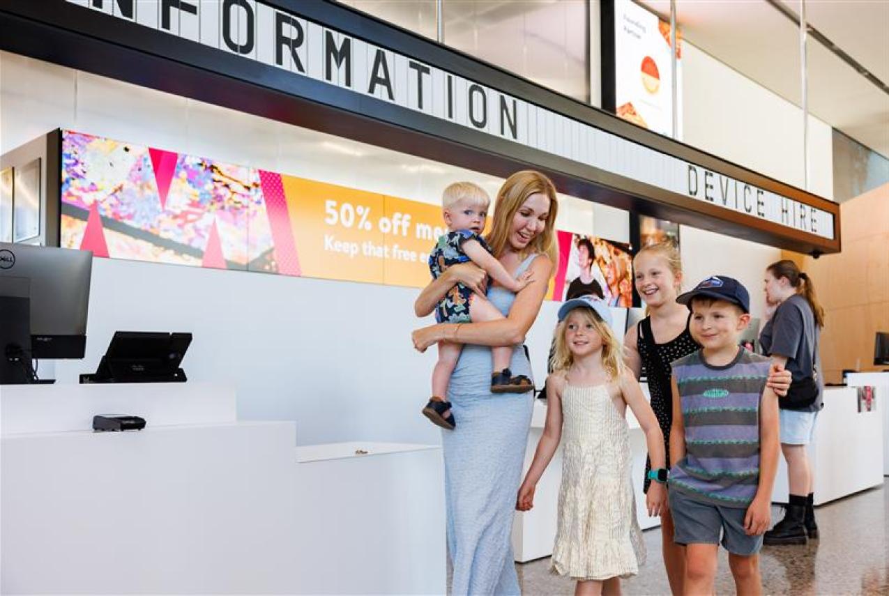 Family leaving front counter with 50 per cent off messaging in the background