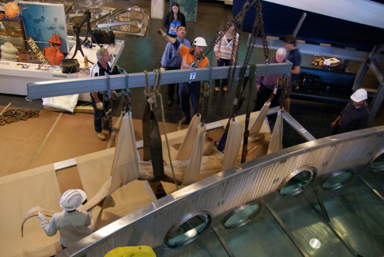 People use chains and slings to lift an object in a museum.