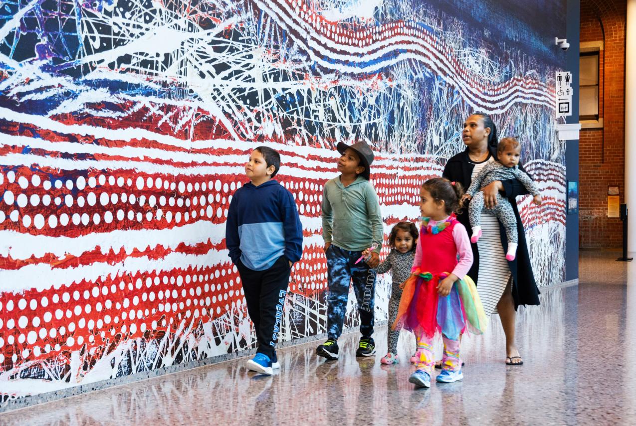 A family walking through the Museum beside a large-scale artwork print.