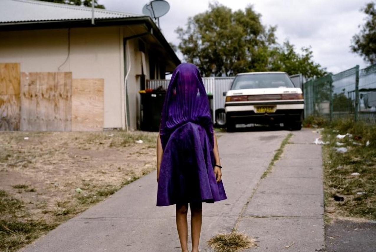Laurinda, a young Kamilaroi girl from Moree, New South Wales, plays with her purple dress while she waits for the bus that will take her to Sunday School. She is among the many socially isolated young women in disadvantaged communities in Australia facing