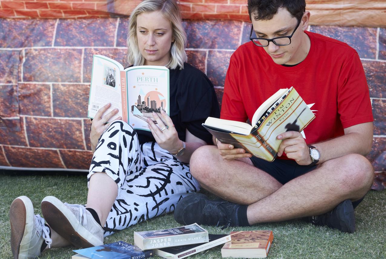 A man and woman reading books about Western Australia