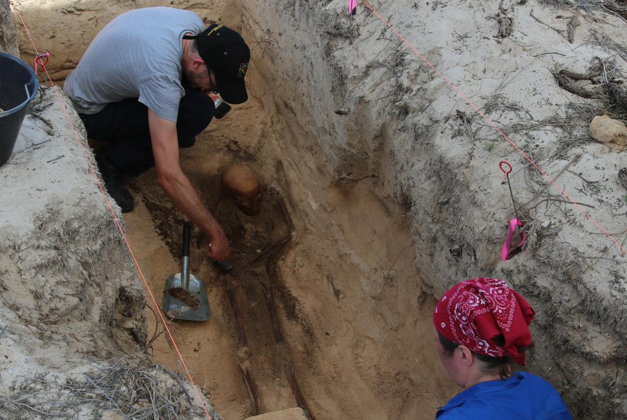 Two researchers carefully excavating a burial site at Beacon Island, 2015