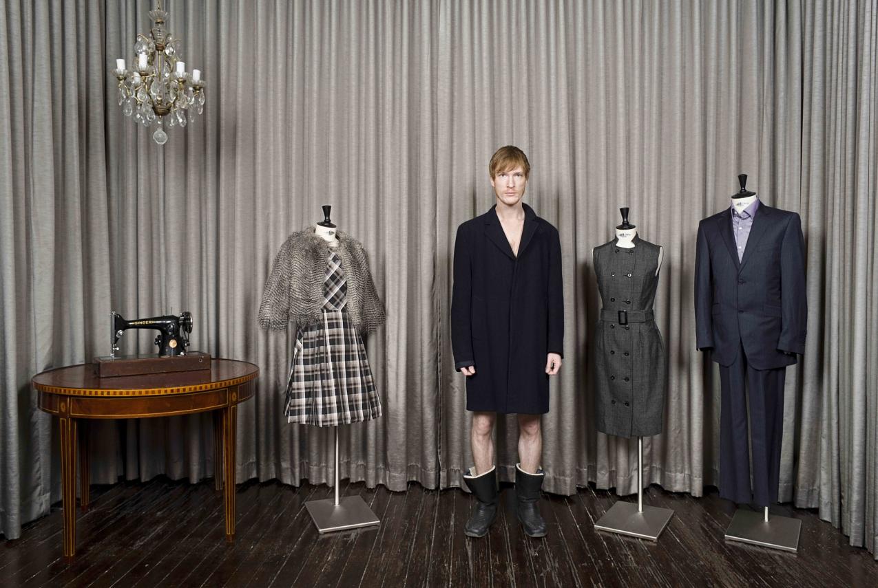Man photographed next to clothes on mannequins
