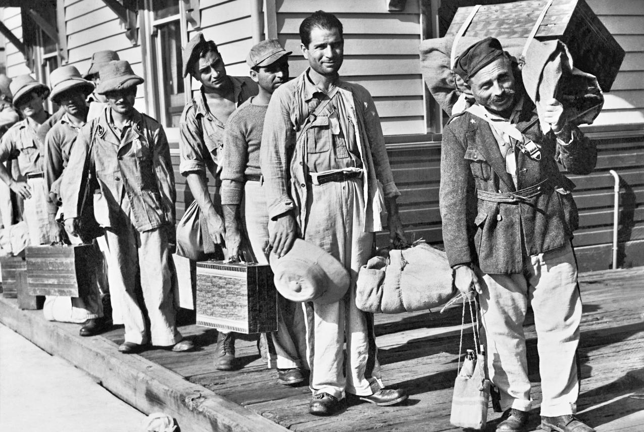Italian prisoners of war carrying their their luggage wait to board a train bound for an Australian camp in 1943