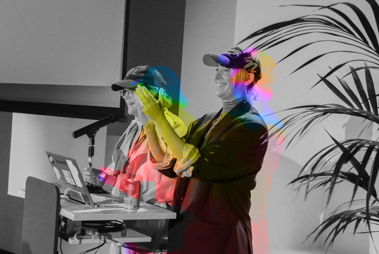 Queer Powerpoint hosts Xanthe Dobbie and Harriet Gilles clap and present during Queer PowerPoint at WA Museum Boola Bardip.