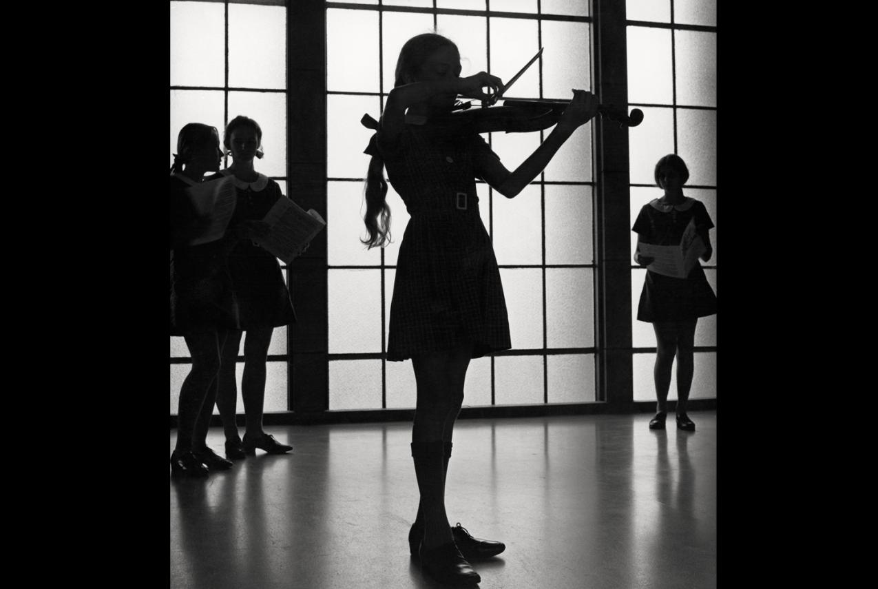A silhouette of a child playing violin