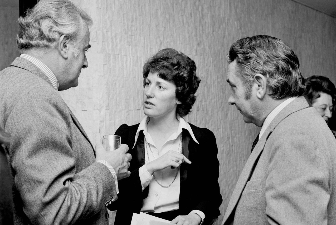 Black and white photograph of three people talking.