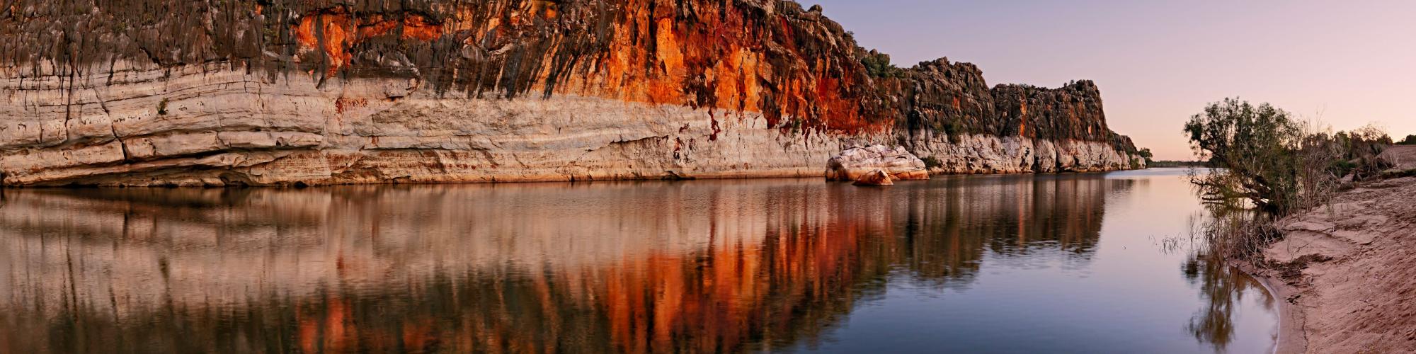 Danggu Geikie Gorge Twilight, a cliff face going into the river at sunset, with reflections on the water