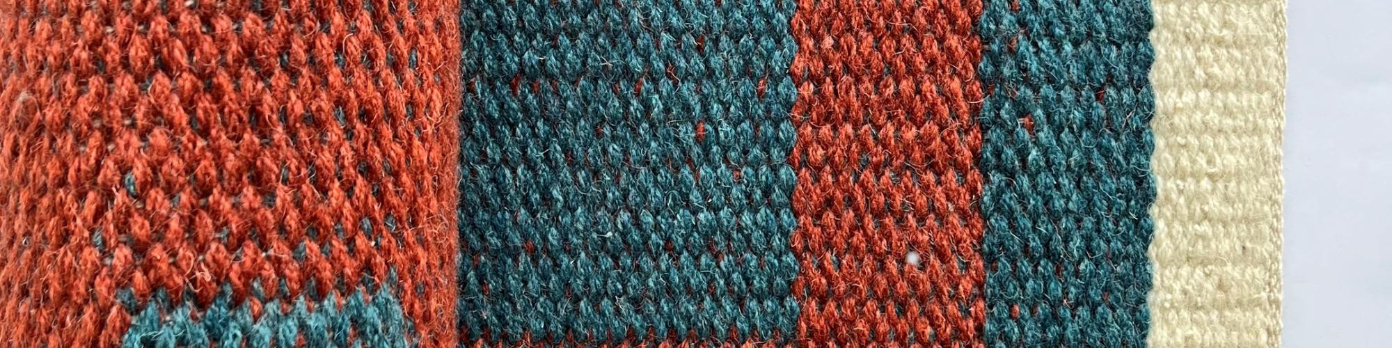 a close up of red and blue colour yarn weaved into a pattern