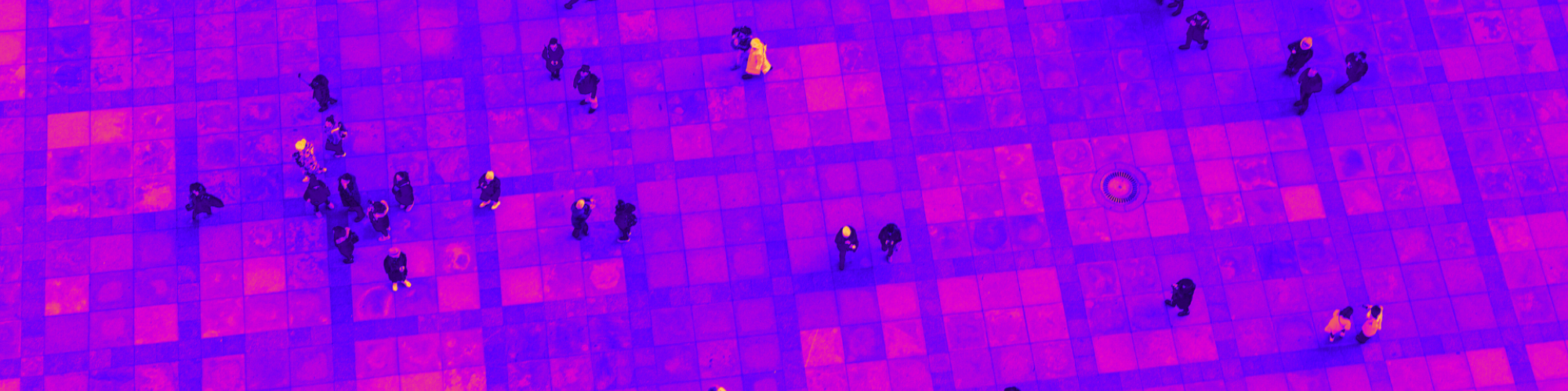 Aerial view of a tiled plaza with a purple and pink overlay, featuring scattered people and long shadows.