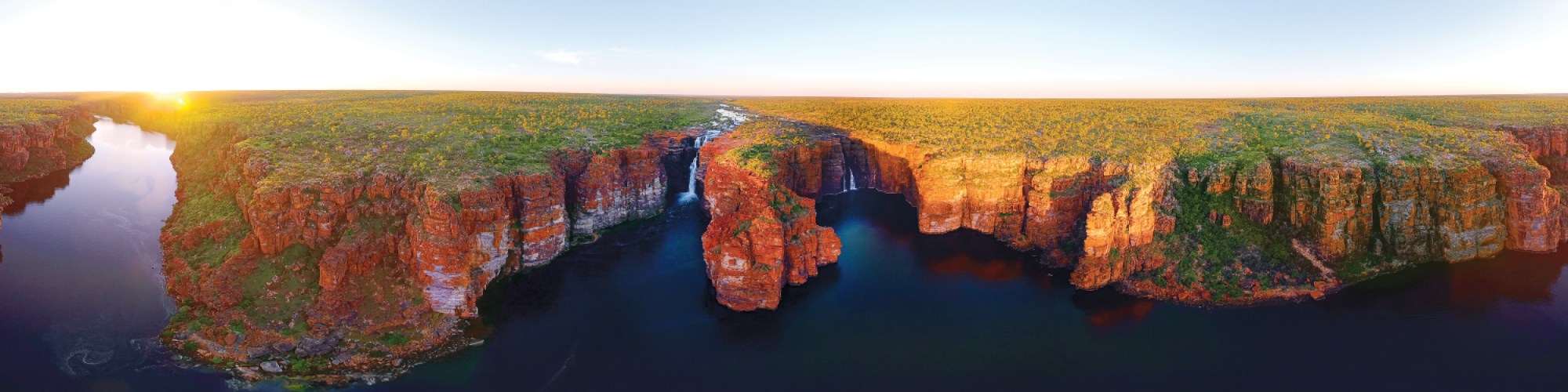 a landscape with ocean in the foreground and cliffs with waterfalls 