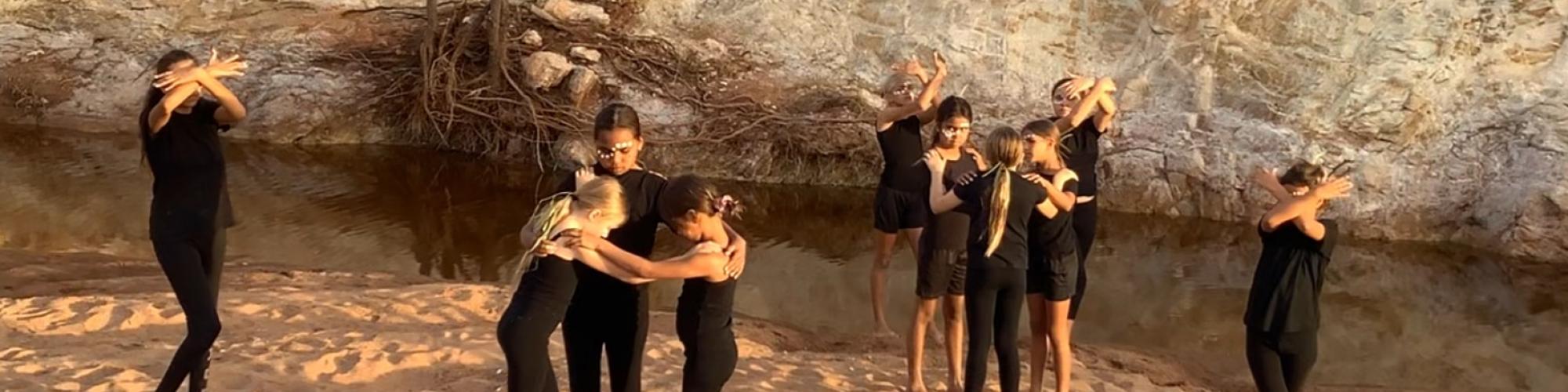 a group of young people stand in poses on the sand