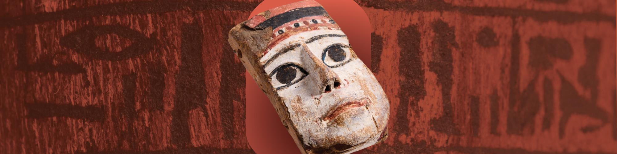 a painted mask object on a background of hieroglyphics