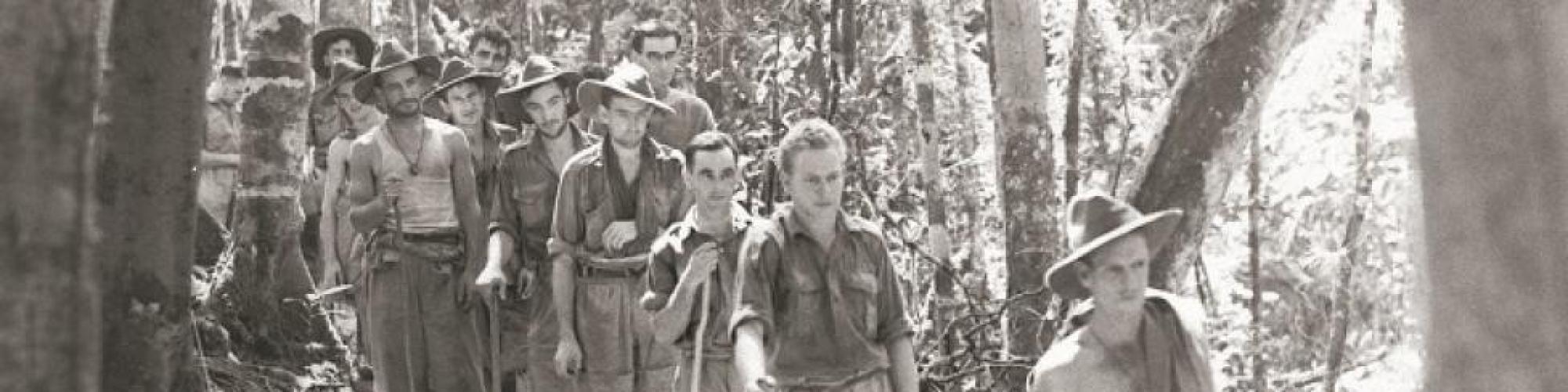 a black and white picture of soldiers walking in a line outdoors