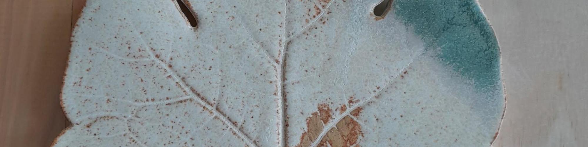 a close up of a ceramic leaf painted in greens and browns