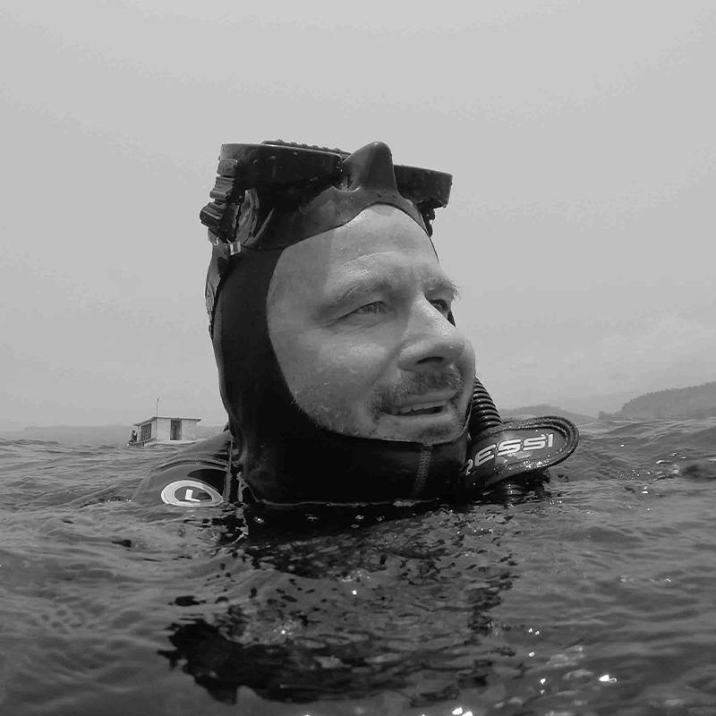 A man wearing diving equipment floats on the surface of the ocean