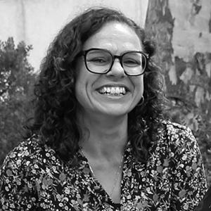 A black and white photo of a women with black framed reading glasses