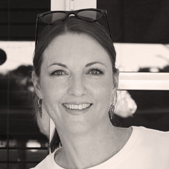 A black and white photo of a women with sun glasses on her head