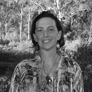 A black and white photo of a woman in a floral top with trees in the background