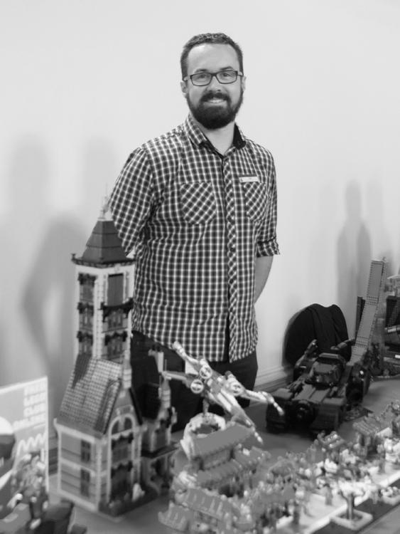 A man stands behind a display of LEGO models