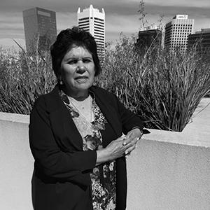 A black and white photo of a women leaning on a white wall
