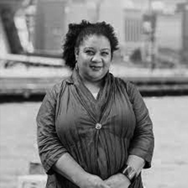 A black and white photo of a women with a river in the background 