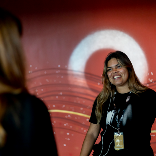 A museum tour guide smiles at a visitor at the entrance to a gallery