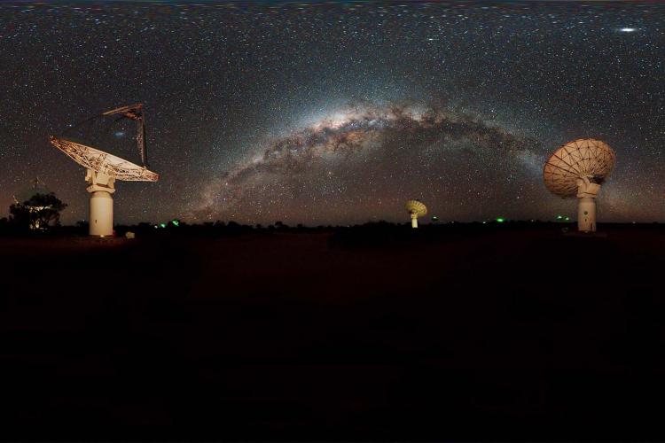 A field of radio telescope antennae lit up under a starry night sky