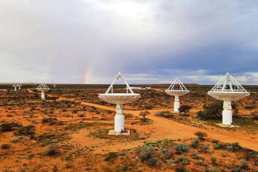 A field of radio telescope antennae under a cloudy sky