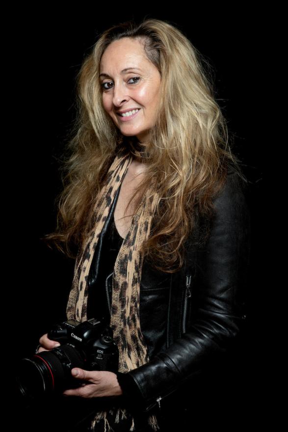 Head shot of Martine Perret holding a camera wearing a scarf
