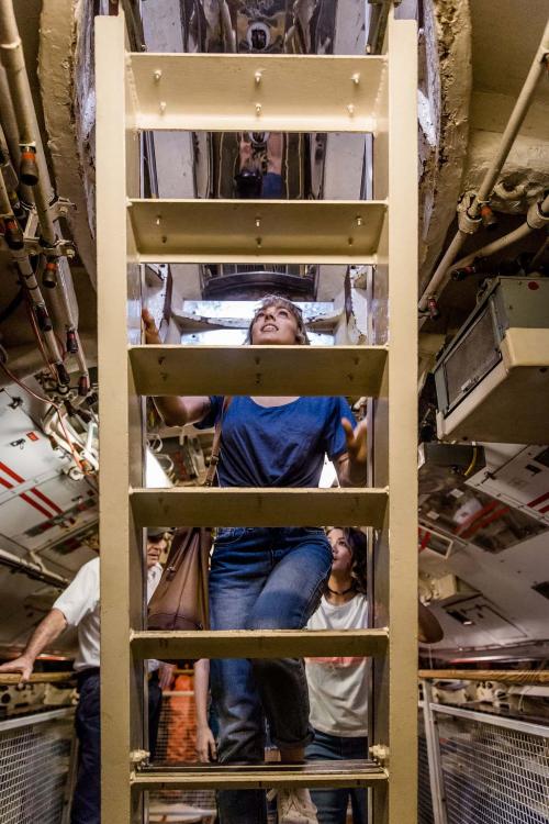 A participant on the immersive tour of the HMAS Ovens climbs a ladder