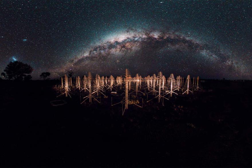 A field of radio telescope antennae under a starry night sky