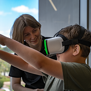 A person using a VR headset with another person looking on