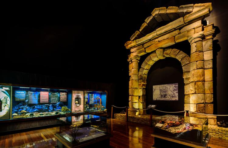 Stone archway in a gallery with displays in the background.