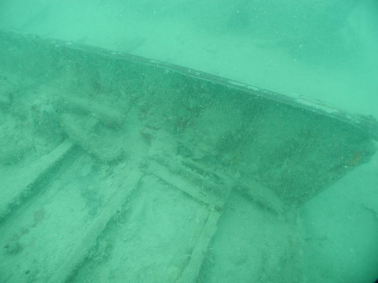 Section of fuselage underwater, covered in marine sediment.