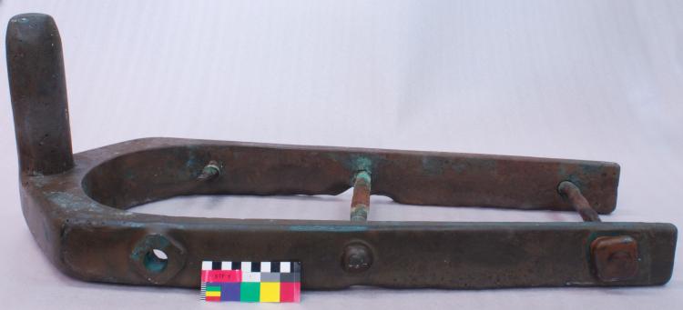 Side view of a large horseshoe shaped piece of metal with a verticle shaft at the top end.